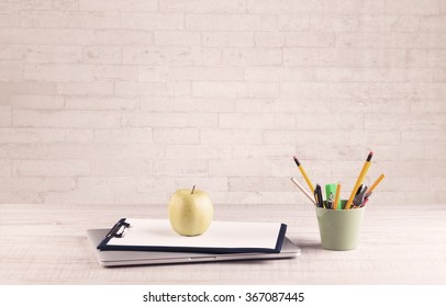 Close up of business office desk with pen board coffee in front of empty white brick textured wall background.