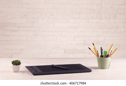 Close up of business office desk with pen board coffee in front of empty white brick textured wall background.