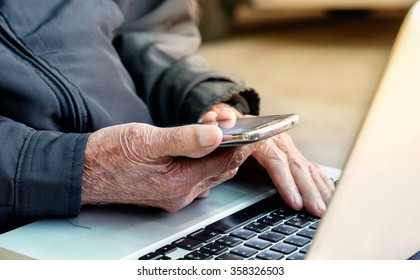 Close Up Of A Business Old Man Using Mobile Smart Phone And Laptop