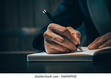 Close Up Of Business People Hand In Suit Writing On Notebook Or Document