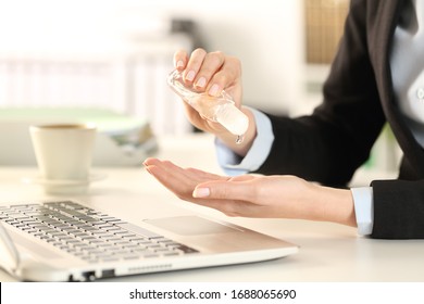 Close up of business woman cleaning hands with sanitizer sitting on a desk in the office - Powered by Shutterstock