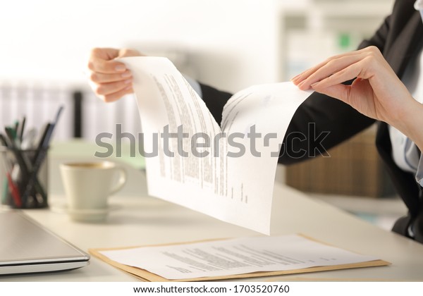 Close up of business woman hands\
breaking contract document sitting on a desk at the\
office