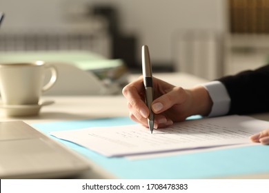Close up of business woman hands filling out form at night in the office
