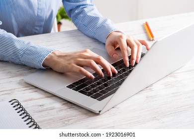 Close up business woman hands typing at laptop keyboard. Side view office workplace with computer on white wooden table. Professional business occupation design with secretary working at desk.