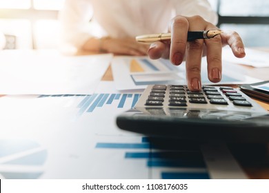 Close up Business woman using calculator and laptop for do math finance on wooden desk in office and business working background, tax, accounting, statistics and analytic research concept - Shutterstock ID 1108176035