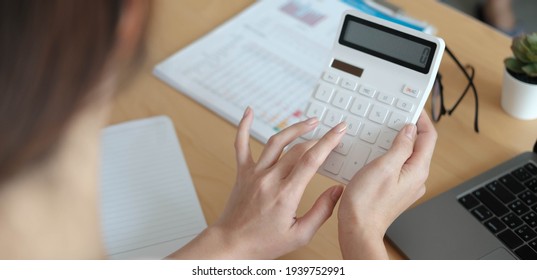 Close up Business woman using calculator and laptop for do math finance on wooden desk in office and business working background, tax, accounting, statistics and analytic research concept