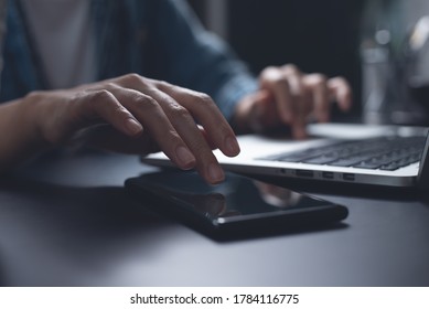Close up of business woman using mobile smart phone, working on laptop computer, browsing internet at home office at night, online working, overtime job, business and technology concept - Shutterstock ID 1784116775