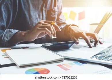 Close up of businessman or accountant hand holding pencil working on calculator to calculate financial data report, accountancy document and laptop computer at office, business concept - Shutterstock ID 717032236