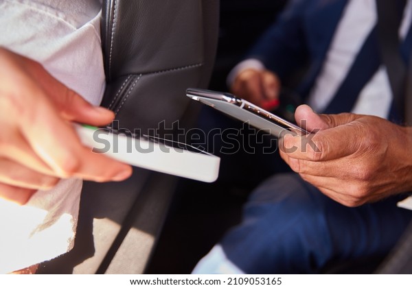 Close Up Of Businessman In\
Back Of Taxi Paying Fare Using Contactless Payment App On Mobile\
Phone