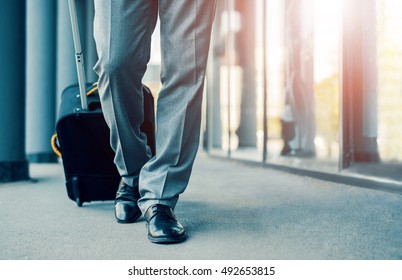 Close up of businessman carrying suitcase while walking through a passenger boarding bridge.