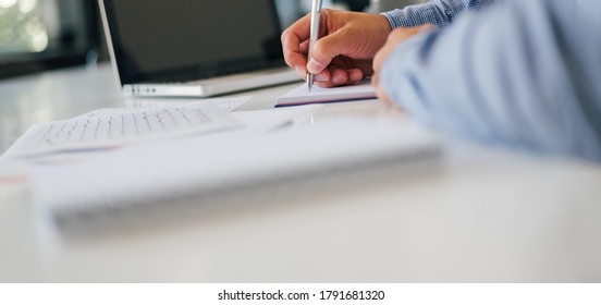 Close up of businessman entrepreneur hand taking notes holding using pencil pen in modern bright office against laptop notebook computer empty dark screen and planing writing taking notes interview - Powered by Shutterstock - Get 15% off with code: PIKWIZARD15