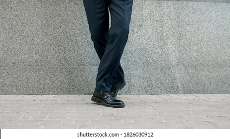 Close up businessman feet dancing in slow motion outside near wall. Business man leg dancing at street. Happy businessman dancing in black shoes outdoor.