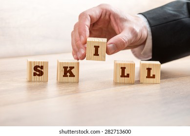 Close up Businessman Hand Arranging Wooden Blocks on Top of the Table to Form Skill Word.
