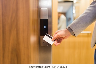 Close up of businessman hand holding key card to unlock elevator access, corporate building security concept.