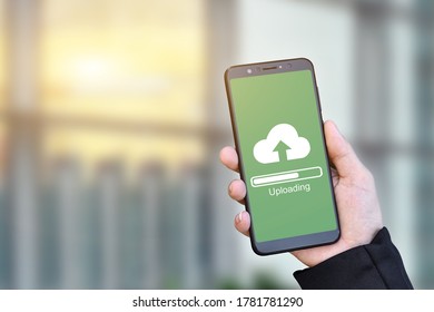 Close Up Of Businessman Hand Holding Mobile Smartphone With Cloud Upload To Store Data On Server.