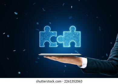Close up of businessman hand holding mobile phone with glowing digital blue jigsaw puzzle hologram on dark blurry background. Digital solution, collaboration, partners , merge, matching concept - Shutterstock ID 2261352063