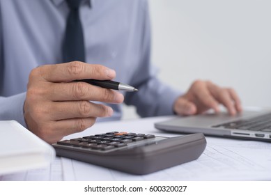 Close up of businessman hand holding pen working on calculator, accountancy document and laptop computer at office, e business concept - Shutterstock ID 600320027