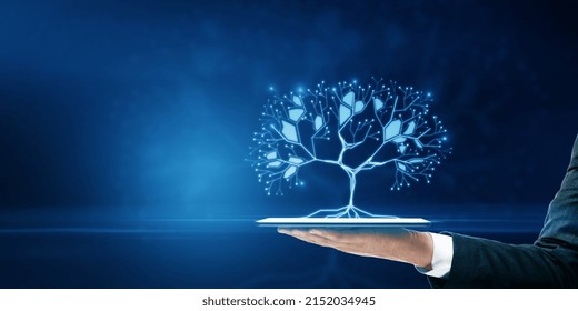 Close up of businessman hand holding tablet with glowing digital polygonal tree on blue background with mock up place. Network, technology and database concept - Shutterstock ID 2152034945