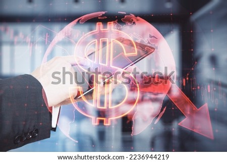 Close up of businessman hand pointing at mobile phone with falling global red dollar arrow hologram on blurry background. Market fall, recession and finance concept. Double exposure