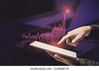 Close Up Of Businessman Hand Pointing At Tablet With Abstract Glowing Growing Global Business Chart On Blurry Officr Desktop Background. Financial Growth And Trade Concept. Double Exposure