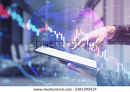 Close up of businessman hand pointing at tablet with glowing downward candlestick forex chart on blurry office interior background. Crisis, financial loss and crash concept. Double exposure