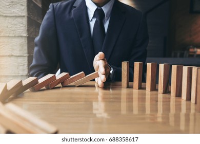 Close up of businessman hand Stopping Falling wooden Dominoes effect from continuous toppled or risk, strategy and successful intervention concept for business. - Powered by Shutterstock