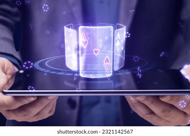 Close up of businessman hands holding tablet with creative digital blue cards hologram on dark background. Online casino, poker and digital gaming concept