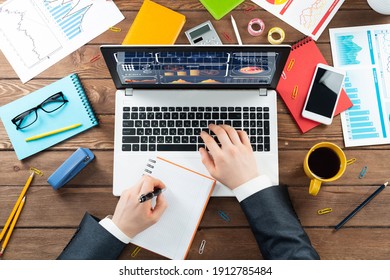 Close up businessman hands working at laptop. Top view office workplace with computer and financial documents on wooden table. Business occupation design with man in business suit sitting at desk