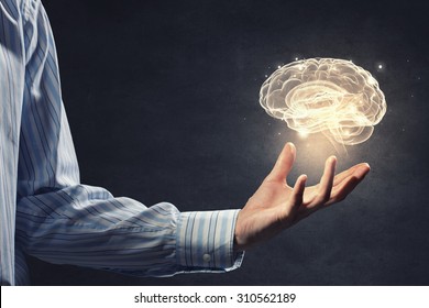 Close up of businessman holding digital image of brain in palm - Shutterstock ID 310562189