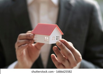 Close Up Of Businessman Holding Model House. Architecture, Building, Construction, Real Estate And Property Concept 
