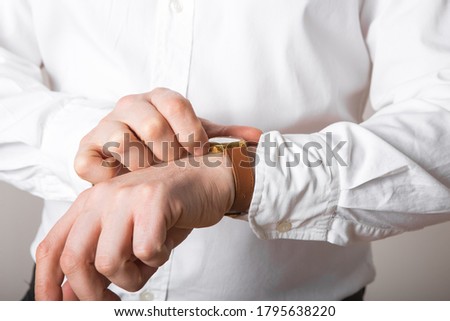 Close up of businessman looking at watch on his hand free space. Man in white shirt checking time from luxury wristwatches. Groom wedding preparation.