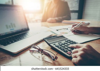 Close up Businessman and partner using calculator and laptop for calaulating finance, tax, accounting, statistics and analytic research concept