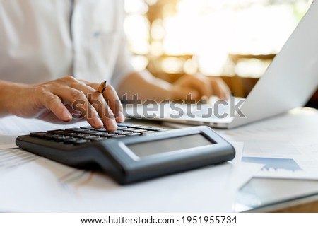 Close up businessman pressing on calculator for calculating cost estimating with laptop.