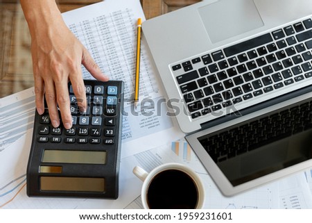 Close up businessman pressing on calculator for calculating cost estimating with laptop.