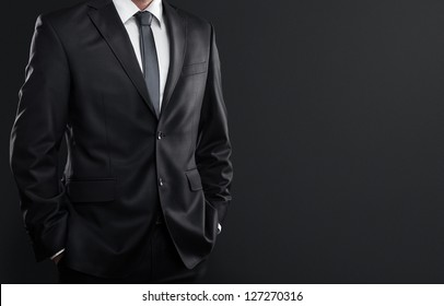 Close up of businessman in suit over dark gray background with copy space