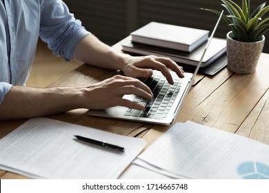 Close up businessman using laptop, typing on keyboard, sitting at wooden desk with documents, writing email, accountant writing financial report, busy student studying online, searching information