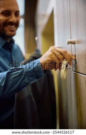 Close up of businessman using locker while changing clothes in gym's dressing room. 