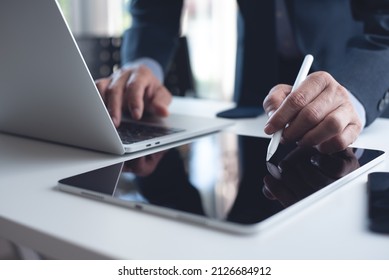 Close Up Of Businessman Using Stylus Pen Signing Contract On Digital Tablet With Laptop Computer On Office Table. Business Man Manager Proofing E-document, Electronic Signature, E-signing Mobile App