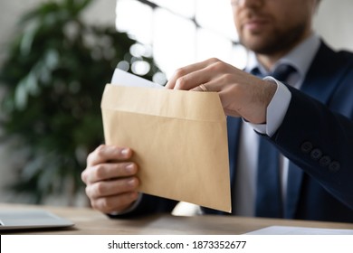 Close up businessman wearing suit holding opening paper envelope with letter in office, sitting at desk, working with correspondence, executive employee received news or important information
