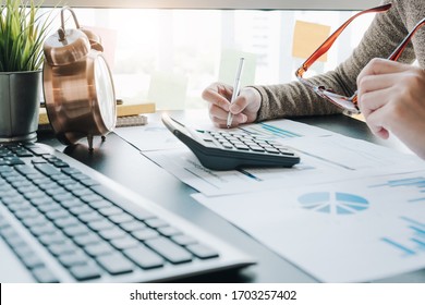 Close up of businesswoman or accountant hand holding pen working on calculator to calculate business data, accountancy document and laptop computer at office, business concept - Shutterstock ID 1703257402