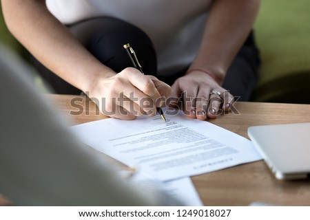Close up of businesswoman hand holding ballpoint after checking official paper ready to sign agreement. Female affirming contract with signature. Concept of collaboration, trust and successful deal