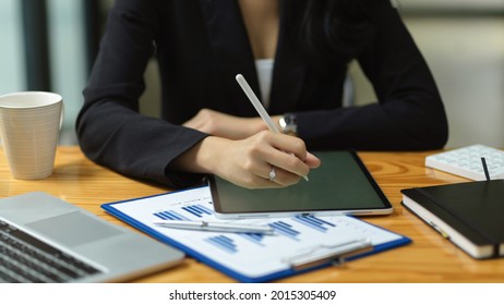 Close Up Of Businesswoman Hand Are Working On Smart Digital Tablet At Office, Working On Financial Statement Online, Stylus Pen, Reports, Laptop On Wooden Table