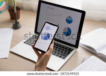 Close up businesswoman holding working with project statistics on devices, presentation with graphs and diagrams on laptop and phone screens, entrepreneur accountant analyzing financial data