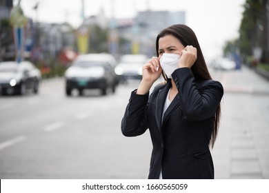Close up of a businesswoman in a suit wearing Protective face mask and cough, get ready for Coronavirus and pm 2.5 fighting against beside road in background. - Shutterstock ID 1660565059