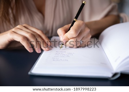 Close up businesswoman writing in notebook, planning workday, meetings, entrepreneur managing time, sitting at table, student making note during lecture, preparing for exam, handwriting