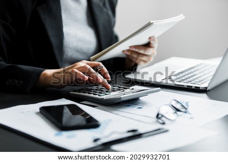 Close up of businesswomen or accountant using calculator calculate while working analytic business report on the workplace, Planning financial and accounting concept.