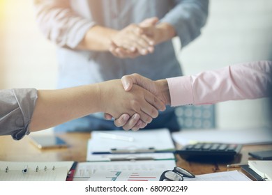 Close Up Of Bussiness  Shaking Hands .(laptop  ,paper And Safety Helmet) Team Meeting Concept 
