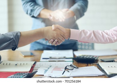 Close Up Of Bussiness  Shaking Hands .(laptop  ,paper And Safety Helmet) Team Meeting Concept 
