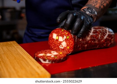 Close up Butcher hands that slicing handmade sausage in a butchers kitchen. Male hands placing a sausage on the cutting table. - Powered by Shutterstock