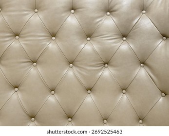 Close up of button tufted upholstered panel with beige leather. Seamless background texture.